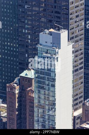 325 Lexington Avenue ist ein Hochhaus mit Glaskastenhäusern, das über einem benachbarten fünfstöckigen Sandsteingebäude im Murray Hill-Bereich von Manhattan schwebt. Stockfoto