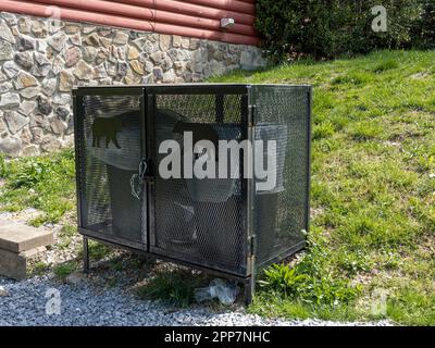 Neben einer Blockhütte in den Smokey Mountains in der Nähe von Pigeon Forge, Tennessee, USA, befinden sich bärensichere Müllcontainer oder Anti-Bär-Mülltonnen. Stockfoto