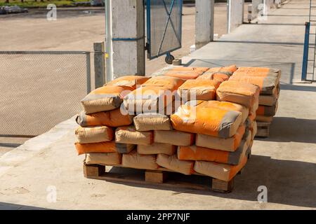 Zementsäcke werden auf Paletten gelagert und in Lagerhäusern gelagert. Säcke mit Zement wurden aus dem Lager auf die Rampe entladen und für den Versand an vorbereitet Stockfoto