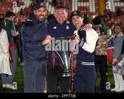 Wrexham Miteigentümer Ryan Reynolds (links), Rob McElhenney (rechts) und Manager Phil Parkinson (Mitte) feiern die Beförderung zur Sky Bet League 2 nach dem Spiel der Vanarama National League auf dem Rennplatz Wrexham. Foto: Samstag, 22. April 2023. Stockfoto