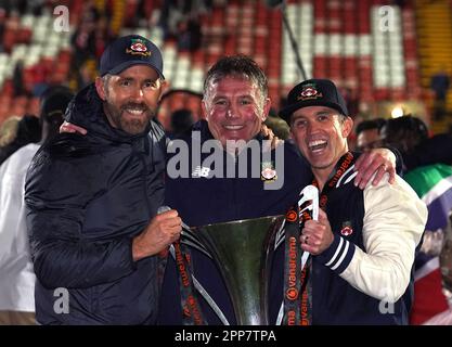 Wrexham Miteigentümer Ryan Reynolds (links), Rob McElhenney (rechts) und Manager Phil Parkinson (Mitte) feiern die Beförderung zur Sky Bet League 2 nach dem Spiel der Vanarama National League auf dem Rennplatz Wrexham. Foto: Samstag, 22. April 2023. Stockfoto