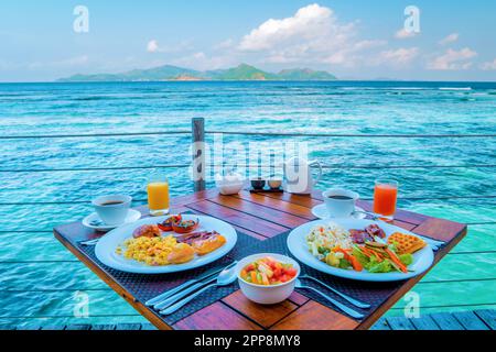 Frühstück am Strand am Pool mit Blick auf das Meer der tropischen Insel La Digue Seychelles an einem sonnigen Tag Stockfoto