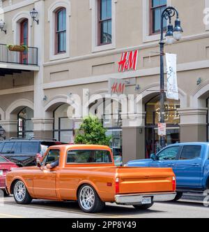 NEW ORLEANS, LA, USA - 2. APRIL 2023: Vor dem French Quarter H&M Store mit klassischem Pick-up im Verkehr Stockfoto