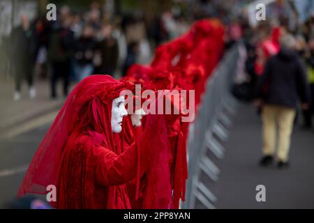 London, Großbritannien. 22. April 2023. Demonstranten sahen sich verkleidet, als rote Brigaden Händchen hielten, um die britische Regierung zu drängen, die Klimakrise während des marschs vor dem britischen Parlament als eine Notlage zu betrachten. Aussterbende Rebellionen, eine massenhafte Gruppe von Aktivisten aus verschiedenen Disziplinen, die sich in erster Linie um die Klimakrise sorgen, setzen ihre Massenkampagne am Tag der Erde fort. Dies ist die erste Kampagne, seit sich die Gruppe seit Ende letzten Jahres verpflichtet hat, von kontroversen disruptiven Methoden abzuweichen. (Foto: Hesther Ng/SOPA Images/Sipa USA) Guthaben: SIPA USA/Alamy Live News Stockfoto