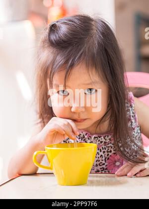 Hübsches asiatisches Mädchen, das mit einem Strohhalm trinkt Stockfoto