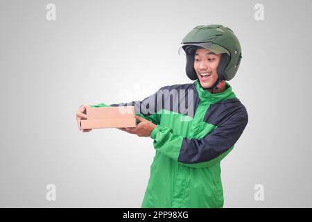 Porträt eines asiatischen Online-Kurierfahrers mit grüner Jacke und Helm, der Paket und Box für den Kunden liefert. Isoliertes Bild auf weißem Hintergrund Stockfoto