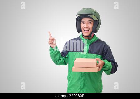 Porträt eines asiatischen Online-Kurierfahrers mit grüner Jacke und Helm, der Paket und Box für den Kunden liefert. Isoliertes Bild auf weißem Hintergrund Stockfoto