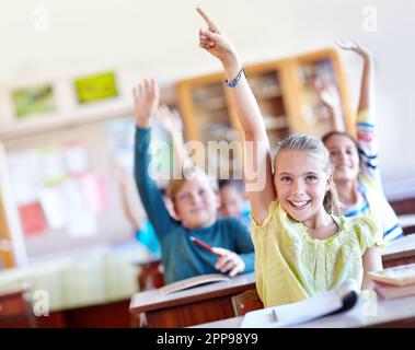 Wir kennen die Antwort. Eine Gruppe von Schulkindern, die ihre Hand in der Klasse heben. Stockfoto