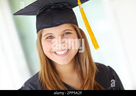 Sie machte ihren Abschluss mit Bravour. Kopf- und Schulterporträt einer hübschen Studentin in ihrem Abschlusskleid. Stockfoto