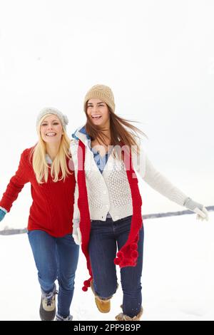 Bleib warm im Schnee. Zwei Freunde laufen zusammen durch den Schnee. Stockfoto