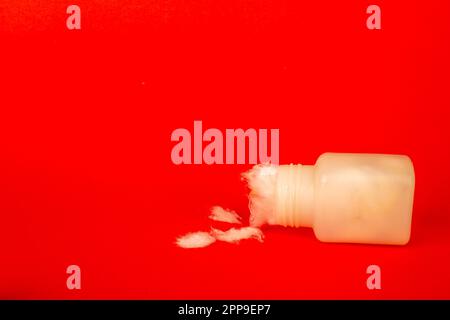 Baumwollfaserstruktur in der weißen Flasche mit iv-Kanüle. Isoliert auf rotem Hintergrund Stockfoto