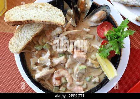 Meeresfrüchte in cremiger Sauce in der Pfanne auf dem Tisch Stockfoto