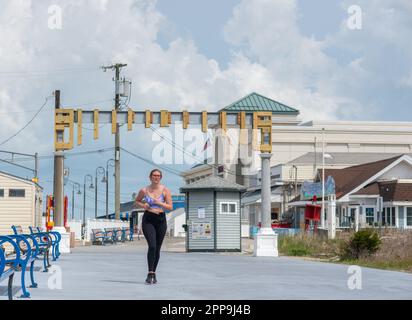 Cape May, Usa. 22. April 2023. Ein Läufer fährt am Samstag, den 22. April 2023, entlang der Promenade in Cape May, New Jersey, durch die im Bau befindlichen Cape May Promenade. Die Torbögen werden als Rückkehr eines malerischen Details des alten Cape May gesehen, dessen ursprüngliche Bögen 1944 durch einen Hurrikan zerstört wurden. ( Kredit: William Thomas Cain/Alamy Live News Stockfoto