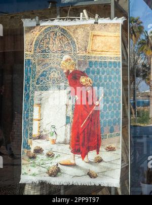 Ein gewebter Teppich, der das berühmte türkische Gemälde namens „Schildkrötentrainer“ darstellt und in einem Geschäft in der antiken Stadt Side in der Türkei verkauft wird. Der Schmerz Stockfoto