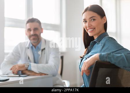 Portrait einer glücklichen Patientin, die medizinische Beratung mit männlichem Arzt erhält, und einer Dame, die vor der Kamera lächelt Stockfoto