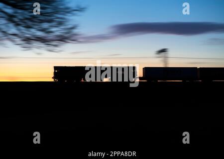 Direct Rail Services Klasse 66 Diesel locomotive66426, der bei Sonnenuntergang einen intermodalen Hochgeschwindigkeits-Containerfrachtzug an der Hauptlinie der Westküste transportiert Stockfoto