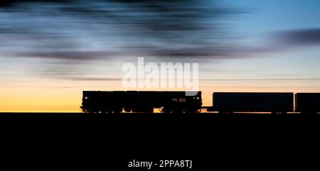 Direct Rail Services Klasse 66 Diesel locomotive66426, der bei Sonnenuntergang einen intermodalen Hochgeschwindigkeits-Containerfrachtzug an der Hauptlinie der Westküste transportiert Stockfoto