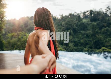 POV-Foto einer Frau, die Hand ihres Freundes hält. Eine Frau, die mit einem Mann zum Schwimmbad führt. Stockfoto