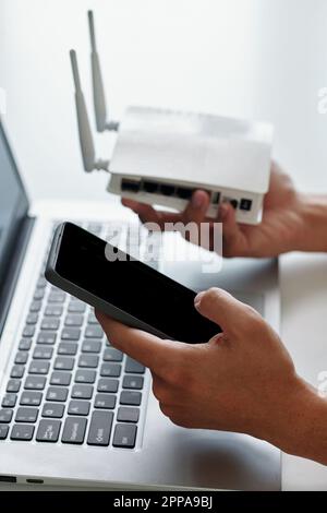 Hände des Entwicklers, der das Smartphone über die Anwendung mit dem wi-Fi-Router verbindet Stockfoto