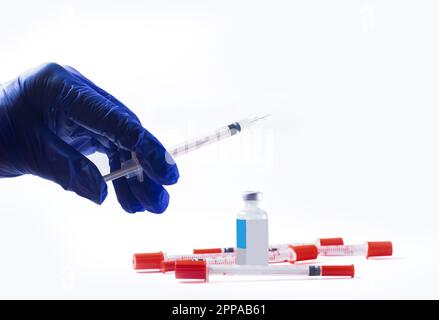 Arzthand in blauen Handschuhen mit Spritze. Durchstechflasche und Spritze auf weiß. Stockfoto