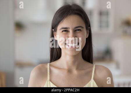 Fröhliches, wunderschönes spanisches Mädchen mit ärmellosem Oberteil, das drinnen posiert Stockfoto