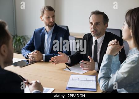 Ein seriöser Geschäftsmann in einem formellen Anzug, der mit Partnern spricht Stockfoto