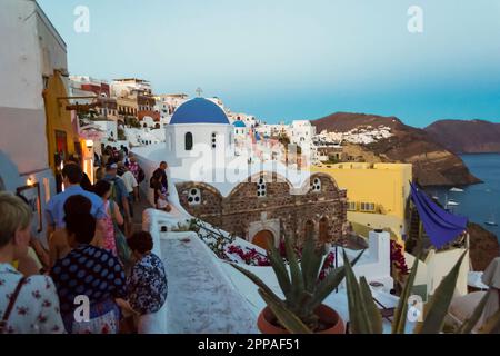 Touristen Sightseeing auf den Nachtstraßen von Oia. Oia ist eine Küstenstadt an der nordwestlichen Spitze von Santorin, griechische Ägäis Insel mit weißen Häusern Stockfoto