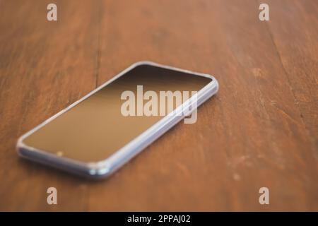 Schwarze Smartphones auf einem braunen Holztisch Stockfoto