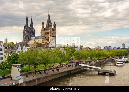 KÖLN, DEUTSCHLAND - MAI 12: Touristen am Rhein in Köln am 12. Mai 2019. Blick auf den Kölner Dom und die große Sain-Martin-Kirche Stockfoto