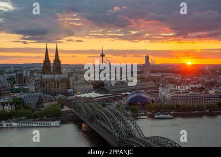 KÖLN, DEUTSCHLAND - 12. MAI: Stadtbild von Köln am 12. Mai 2019 bei Sonnenuntergang. Blick vom Dreiecksturm auf die Kathedrale und Hohenzolern Stockfoto