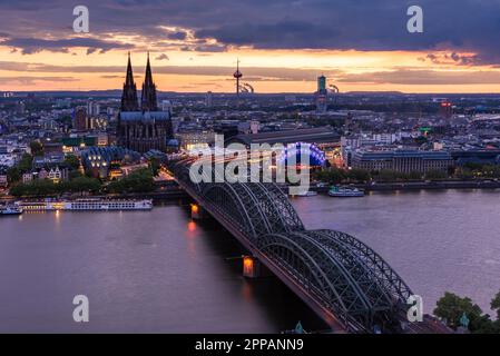 KÖLN, DEUTSCHLAND - 12. MAI: Stadtbild von Köln am 12. Mai 2019 bei Sonnenuntergang. Blick vom Dreiecksturm auf die Kathedrale und Hohenzolern Stockfoto