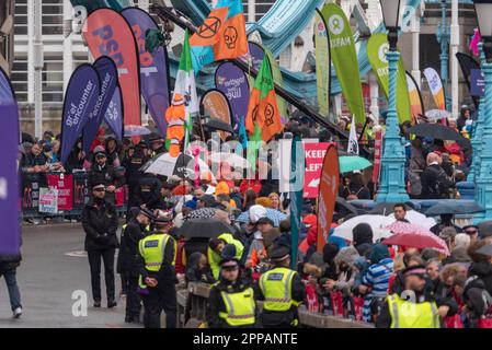 Tower Hill, London, Großbritannien. 23. April 2023. Rund 45.000 Personen nehmen am TCS London Marathon 2023 Teil, darunter die weltbesten Läufer. Polizeibeamte, die Sicherheit um eine Gruppe von Just Stop Oil Demonstranten mit Flaggen in der Nähe der Tower Bridge bieten Stockfoto