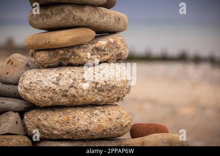 Nahaufnahme eines Haufens von Strandkieseln mit einem Groyne im Hintergrund am Strand von Hornsea Stockfoto