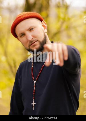 Ein ernster Mann mit einem Kreuz um den Hals, der dir in die Augen schaut Stockfoto