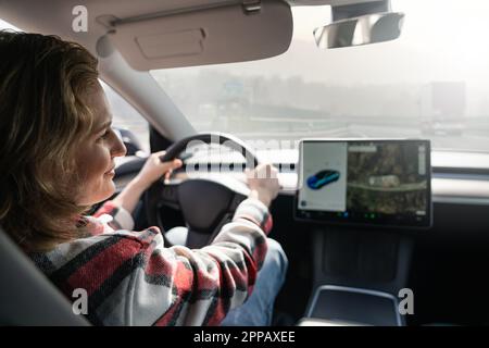 Frau, die ein Elektroauto auf einer Autobahn fährt. Hochwertiges Foto Stockfoto