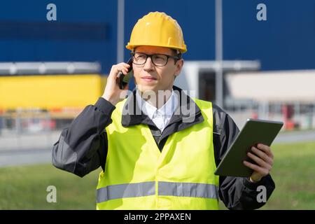 Logistiker mit Telefon und digitalem Tablet im Hintergrund des Logistikzentrums. Hochwertiges Foto Stockfoto