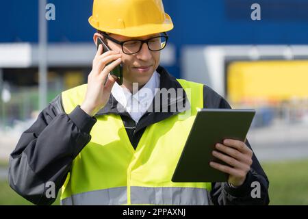 Logistiker mit Telefon und digitalem Tablet im Hintergrund des Logistikzentrums. Hochwertiges Foto Stockfoto