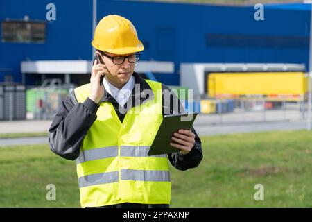 Logistiker mit Telefon und digitalem Tablet im Hintergrund des Logistikzentrums. Hochwertiges Foto Stockfoto