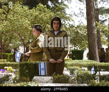 Jerusalem, Israel. 02. Februar 2014. Israelische Soldaten setzen Nationalflaggen mit schwarzen Schleifen auf die Gräber gefallener Soldaten am Mt. Herzl Militärfriedhof in Jerusalem am Sonntag, den 23. April 2023. Israel wird am 24. April den Gedenktag für Soldaten und Terroropfer bei Sonnenuntergang begehen. Foto von Debbie Hill/ Kredit: UPI/Alamy Live News Stockfoto