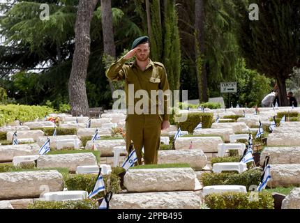 Jerusalem, Israel. 02. Februar 2014. Ein israelischer Soldat salutiert, nachdem er eine Nationalflagge mit schwarzen Bändern auf dem Grab eines gefallenen Soldaten am Mt. Herzl Militärfriedhof in Jerusalem am Sonntag, den 23. April 2023. Israel wird am 24. April den Gedenktag für Soldaten und Terroropfer bei Sonnenuntergang begehen. Foto von Debbie Hill/ Kredit: UPI/Alamy Live News Stockfoto