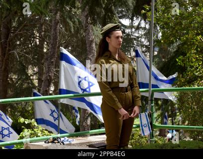 Jerusalem, Israel. 02. Februar 2014. Ein israelischer Soldat hält an, nachdem er eine Nationalflagge mit schwarzen Bändern auf dem Grab eines gefallenen Soldaten am Mt. Herzl Militärfriedhof in Jerusalem am Sonntag, den 23. April 2023. Israel wird am 24. April den Gedenktag für Soldaten und Terroropfer bei Sonnenuntergang begehen. Foto von Debbie Hill/ Kredit: UPI/Alamy Live News Stockfoto