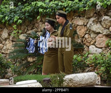 Jerusalem, Israel. 02. Februar 2014. Israelische Soldaten bereiten sich darauf vor, Nationalflaggen mit schwarzen Bändern auf die Gräber gefallener Soldaten am Mt. Herzl Militärfriedhof in Jerusalem am Sonntag, den 23. April 2023. Israel wird am 24. April den Gedenktag für Soldaten und Terroropfer bei Sonnenuntergang begehen. Foto von Debbie Hill/ Kredit: UPI/Alamy Live News Stockfoto