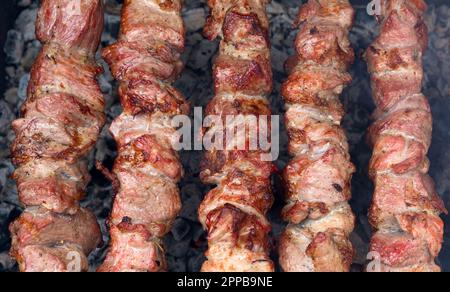 Grillgerichte auf Holzkohle. Shashlik oder Shish Kebab, zubereitet auf heißer Holzkohle. Gegrilltes Schweinefleisch auf Metallspießen. Stockfoto