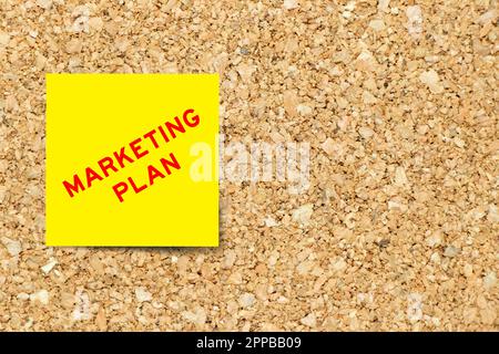 Gelbes Notizpapier mit Word-Marketingplan auf Korkplatten-Hintergrund mit Kopierbereich Stockfoto