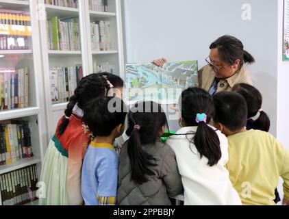 Shanghai, China. 22. April 2023. Kinder lasen ein Bilderbuch auf dem Lebensmittelmarkt der Kuizhao Road in Shanghai, Ostchina, am 22. April 2023. Im Jahr 2010 stellte die Bibliothek des Bezirks Shanghai Hongkou im Lebensmittelmarkt Fuci im Unterbezirk Jiangwanzhen rund 600 Bücher für Wanderarbeitnehmer kostenlos zur Verfügung. Dies war der erste "Lebensmittelmarkt-Leseraum" im Bezirk. Bisher haben dreizehn Lebensmittelmärkte in 8 Unterbezirken des Distrikts Hongkou solche Leseräume eingerichtet, in denen Besitzer von Verkaufsständen und andere Arbeiter eine Pause einlegen können, indem sie lesen und kulturelle Aktivitäten genießen. Kredit: Wang Xiang/Xinhua/Alamy Live News Stockfoto