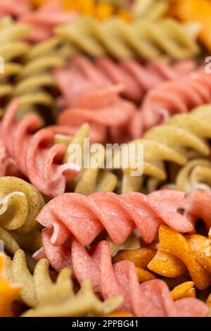 Reisgemüse-Pasta in Spiralform, Draufsicht. Gesunde Reispasta mit Tomaten, Selenera, Karotten und Rüben Stockfoto