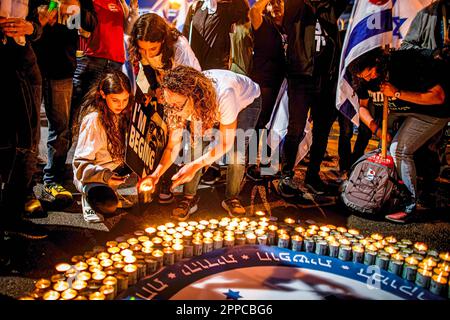 Tel Aviv, Israel. 22. April 2023. Israelis zünden Kerzen an einer Gedenkstätte während einer Anti-Reform-Demonstration in Tel Aviv an. Hunderte von Menschen meldeten sich für die 16. Woche am Samstag gegen Netanjahus Pläne zur Generalüberholung der Gerichte der Koalition. Bei der Hauptproteste in Tel Aviv richteten Mitglieder von Hinterbliebenen ein provisorisches Denkmal mit Kerzen zum Gedenken an gefallene Soldaten ein. Die Familien drängten die Politiker, sich am Memorial Day, der Montag bei Einbruch der Dunkelheit beginnt und Dienstagabend mit dem Beginn des Unabhängigkeitstages endet, von den Friedhöfen fernzuhalten. Kredit: SOPA Images Limited/Alamy Live News Stockfoto