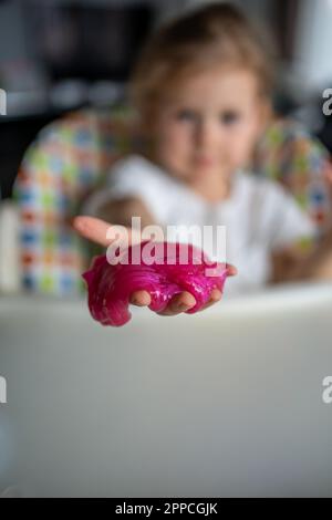 Das kleine Mädchen spielt mit einem hausgemachten rosa Schleim. Kinderhände spielen zu Hause Schleimspielzeug. Stockfoto