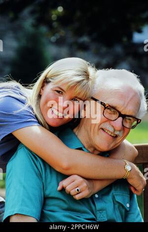 Porträt eines Weißen Seniorenmannes, der von seiner erwachsenen Tochter umarmt wird Stockfoto