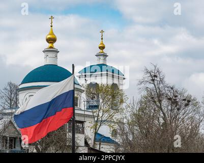 Russische Flagge auf dem Hintergrund von Kirchenkuppeln, Bäumen und fliegenden Vögeln Stockfoto